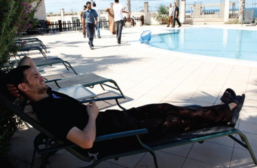 A FORMER Palestinian prisoner released as part of a deal, relaxes by a pool in Gaza in 2011. The author wonders whether prison conditions are much worse (photo credit: REUTERS)