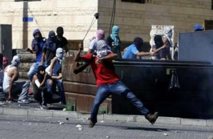  A Palestinian hurls a stone towards Israeli police during clashes in Shuafat, July 2, 2014. (photo credit: REUTERS)