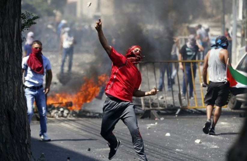 A Palestinian hurls a rock at police in the Wadi al-Joz section of east Jerusalem. (photo credit: REUTERS)