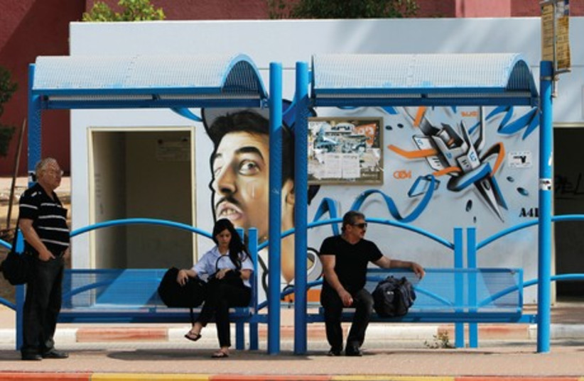 PEOPLE WAIT at a bus stop in Sderot. HopOn is running a pilot with five public transport operators including Kavim in Modi’in, Superbus in Beit Shemesh and the Jerusalem light rail. (photo credit: REUTERS)