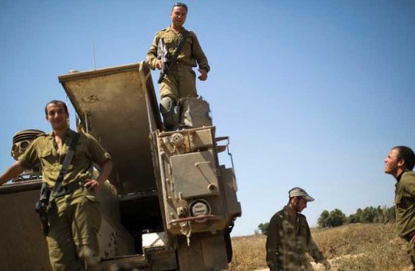 Israeli soldiers stand atop an armored personnel carrier (APC) deployed outside the central Gaza Strip July 6, 2014. (photo credit: REUTERS)