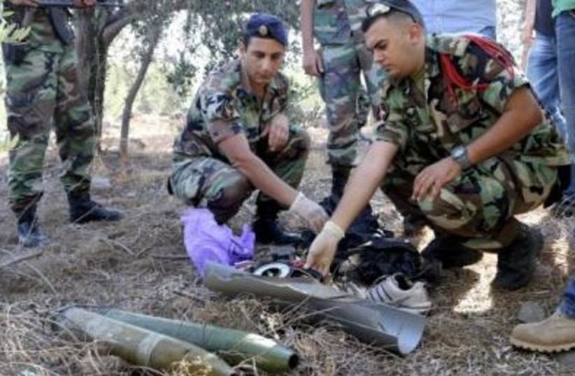 Lebanese army personnel inspect the remains of a shell that was suspected of having been launched from Lebanon to Israel, July 11, 2014. (photo credit: REUTERS)