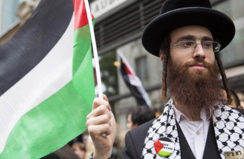 An ultra-Orthodox Jew holds a Palestinian flag during a protest against Israel's air strikes in Gaza in London. (photo credit: REUTERS)