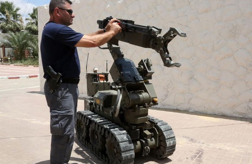 A POLICE SAPPER from the Negev Subdistrict inspects a bomb disposal robot. (photo credit: MARC ISRAEL SELLEM/THE JERUSALEM POST)