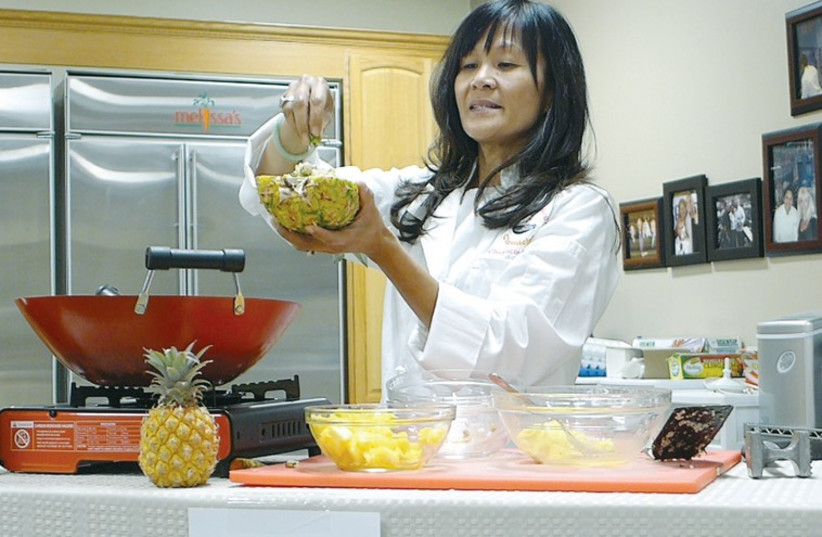 Chef Katie Chin sprinkles fresh herbs for a finishing touch on pineapple fried rice. (photo credit: YAKIR LEVY)