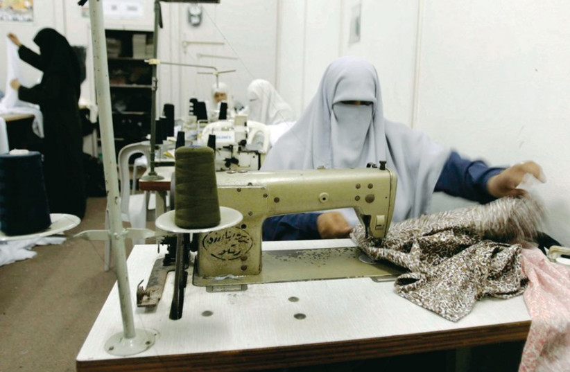 Palestinian woman work in a clothing factory in the southern Gaza Strip in August 2007. Those working in the textile industry in Gaza before 2007 numbered 35,000; today that number is around 3,000. (photo credit: ILLUSTRATIVE: REUTERS)