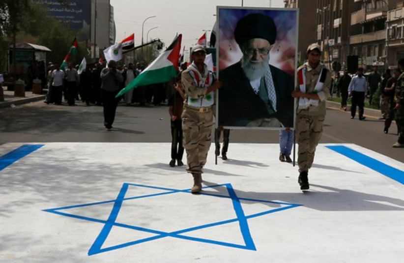 Iraqi muslims from Shi'ite Badr organization hold a portrait of Ayatollah Ali Khamenei as they walk over the Israeli flag during a parade marking Jerusalem Day. (photo credit: REUTERS)