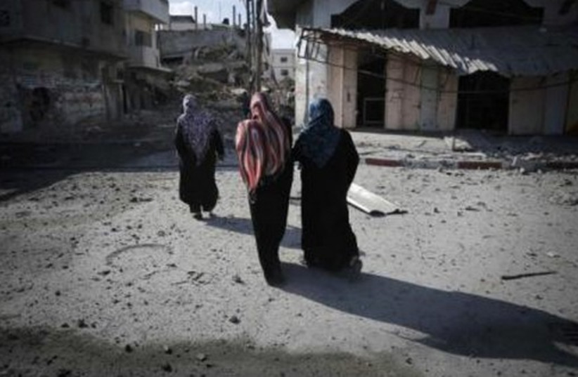 Palestinians walk past destroyed houses in Beit Hanoun in the northern Gaza Strip July 26, 2014.  (photo credit: REUTERS)
