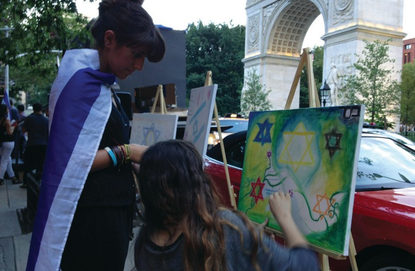 FORMER ROOMMATES Natasha Bassalian (left) and Mazal-Tov Amsellem draw on a canvas set up by Artists 4 Israel during a Thursday evening protest at Washington Square Park in New York City. (photo credit: ANNA HIATT)