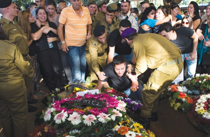 The brother of Sgt. Daniel Kedmi mourns over his grave at the Kiryat Shaul Military Cemetery. (photo credit: RONEN ZVULUN / REUTERS)