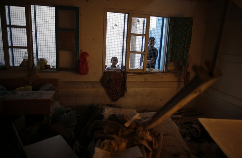 Palestinians look at a damaged classroom in a United Nation-run school (photo credit: REUTERS)