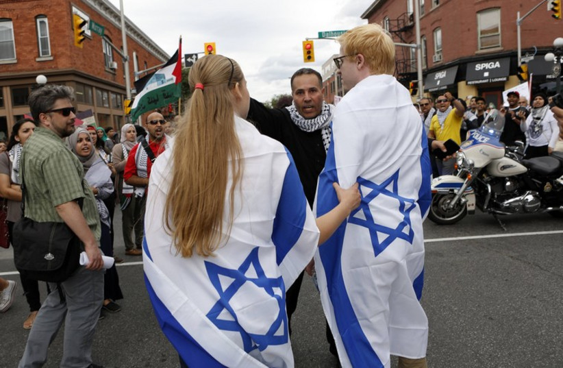 Two people wearing Israeli flags are told to leave by a protest organizer during a pro-Palestinian demonstration against Israel's military action in the Gaza Strip (photo credit: REUTERS)