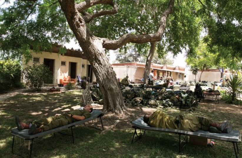 Soldier camp out last month on the lawn in Kibbutz Nir Am, just outside the Gaza Strip. (photo credit: REUTERS)