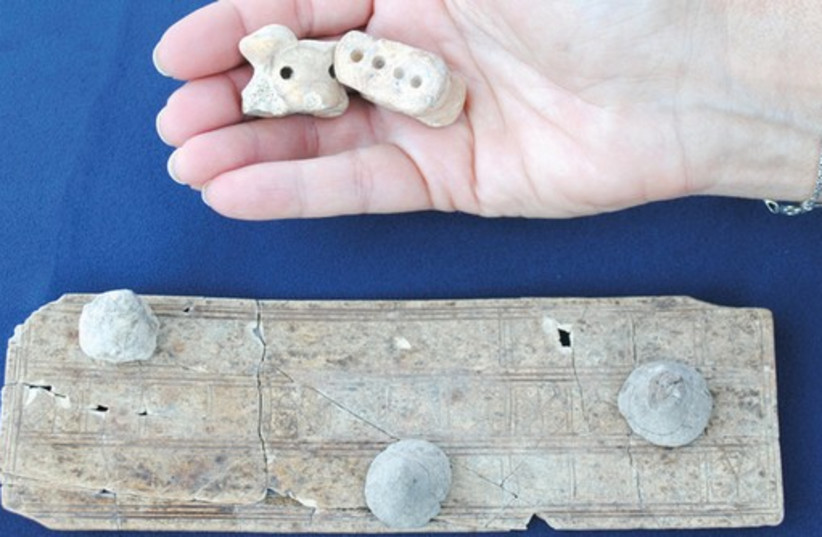 An ancient game board with dice was found recently in the Solomonic city dig at Tel Gezer. (photo credit: ANNIE WEGMAN/TEL GEZER EXCAVATION PROJECT)