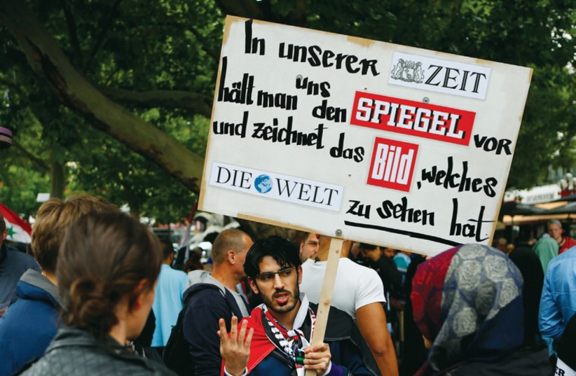 A demonstrator holds a placard during a Muslim protest in Berlin last week against the Israeli assault on the Gaza Strip. (photo credit: REUTERS)