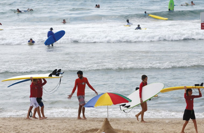 Beachgoers surf the waves in Tel Aviv last week. (photo credit: MARC ISRAEL SELLEM/THE JERUSALEM POST)