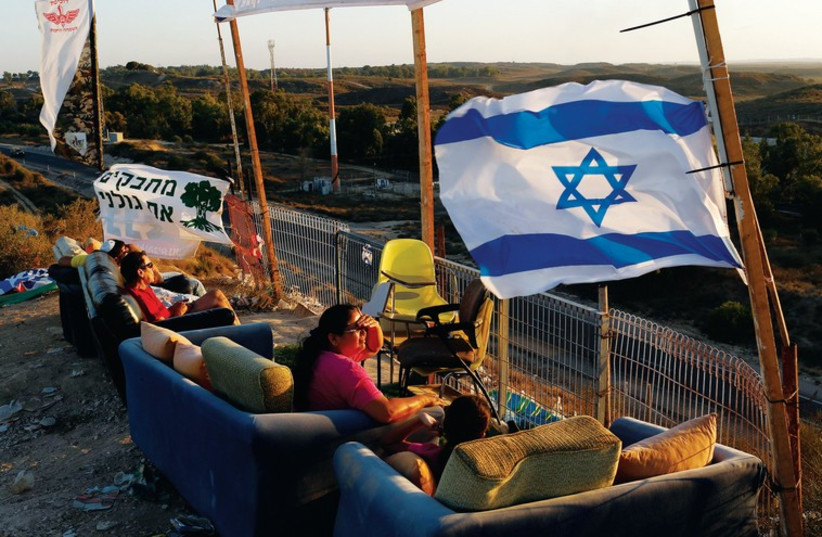 Locals from towns bordering Gaza watch IDF activity from a hill in the region last week. (photo credit: REUTERS)