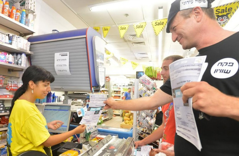 Koby Bremer, a small-grocery owner in Tel Aviv, hands out "fines" to large chains. (photo credit: Courtesy)
