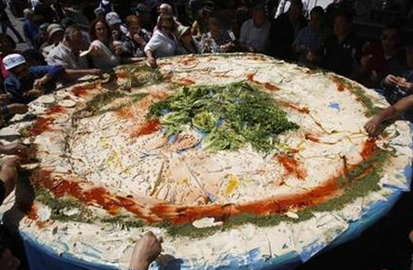 People stand around a large plate of hummus in Jerusalem, May 5, 2008. (photo credit: REUTERS)
