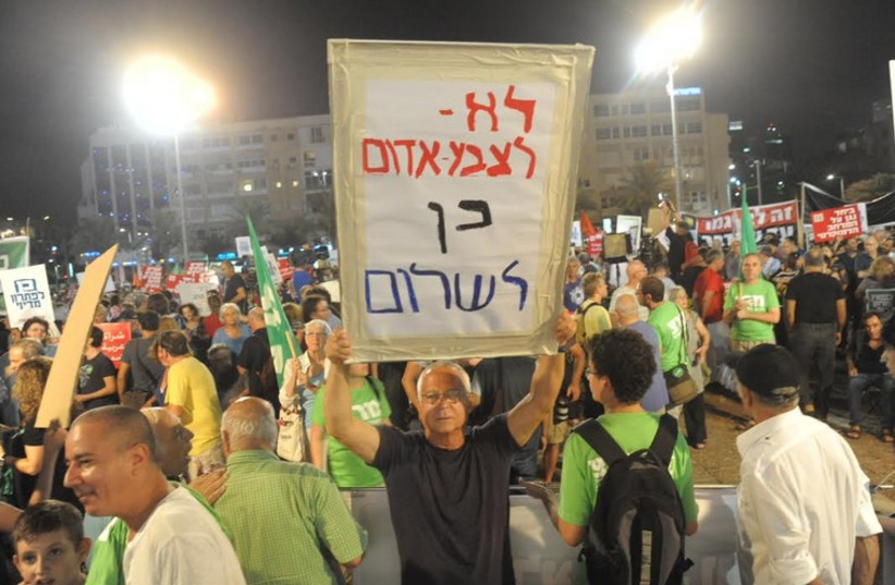 A left-wing protester holds up a sign that reads, "No to Code Red, yes to peace," during Tel Aviv rally. (photo credit: LIOR NOVIK)