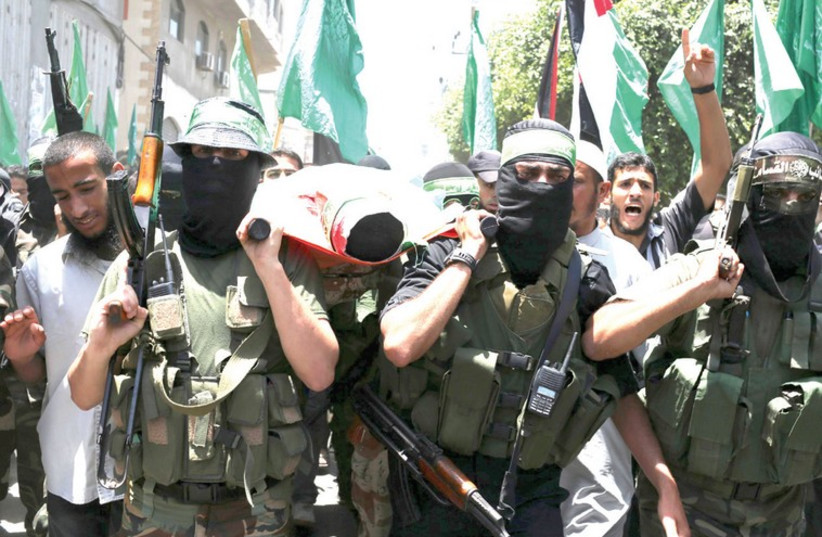 Hamas militants bury a slain comrade in Gaza (photo credit: IBRAHEEM ABU MUSTAFA / REUTERS)