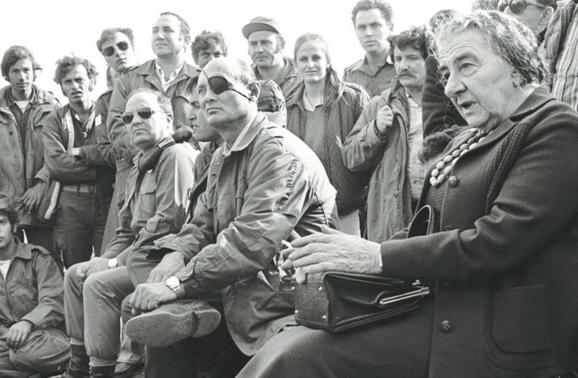 Prime minister Golda Meir, accompanied by defense minister Moshe Dayan, meets with soldiers at a base on the Golan Heights after intense fighting during the 1973 Yom Kippur War. (photo credit: ARCHIVE)