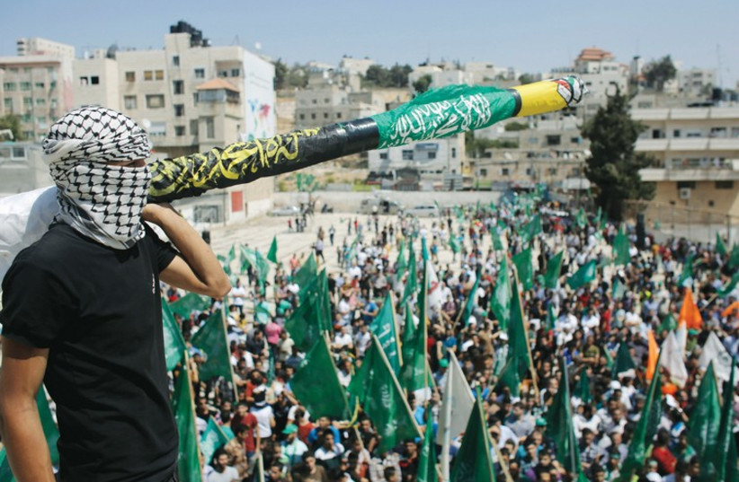 A MASKED Hamas supporter holds a mock missile at a Gaza celebration after last week’s cease-fire. (photo credit: REUTERS)