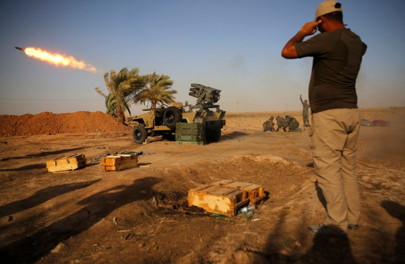 Shi'ite fighters from Mahdi Army launch rockets during heavy fighting against Islamic state members at Bo Hassan village, near Tikrit in northern Iraq. (photo credit: REUTERS)