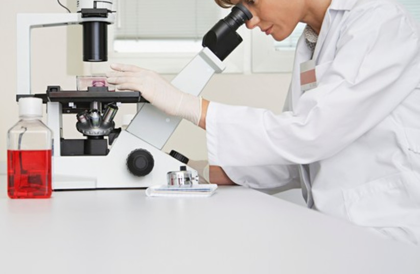 A scientist looks through a microscope (photo credit: INGIMAGE)