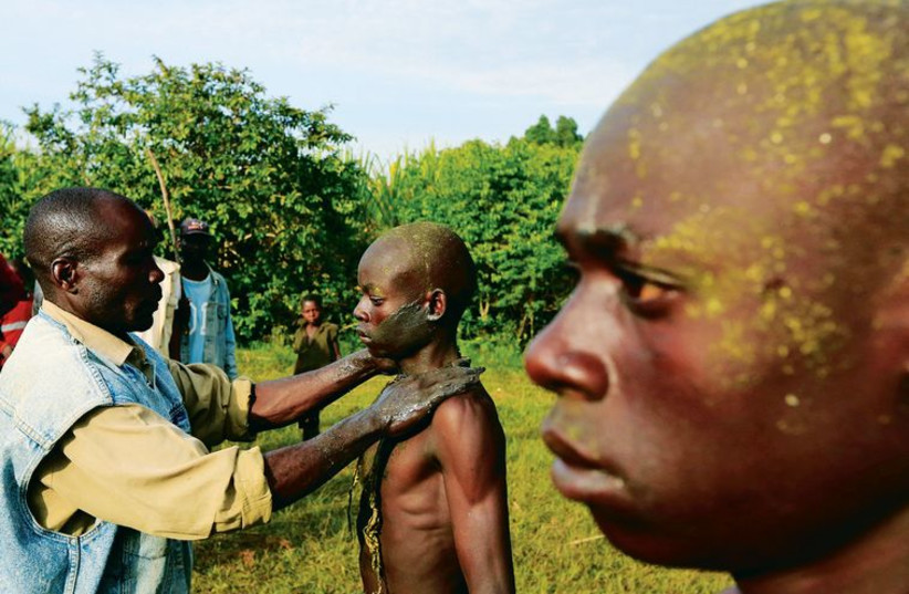 A Bukusu youth is smeared with mud as part of a circumcision ritual in Kenya. (photo credit: REUTERS)