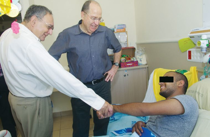 Defense minister Moshe Ya’alon and Prof. Zeev Rotstein visit a wounded soldier at Sheba. (photo credit: YAKOV LEVIT AND ILANA YAACOV FOR SHEBA MEDICAL CENTER)