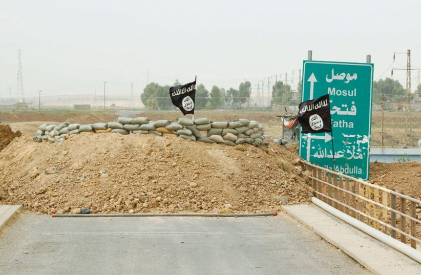 Islamic State flags flutter on the Mullah Abdullah bridge in southern Kirkuk, Iraq, on Monday. (photo credit: REUTERS)