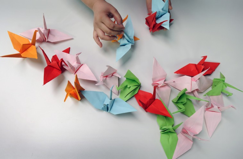 Paper cranes on a table during origami session  (photo credit: REUTERS)