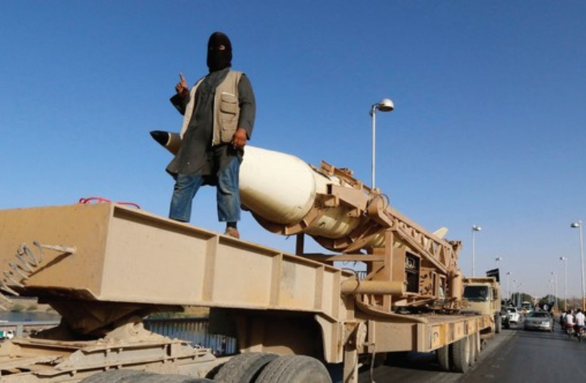 AN ISIS member rides on a rocket launcher in Raqqa in Syria two months ago (photo credit: REUTERS)