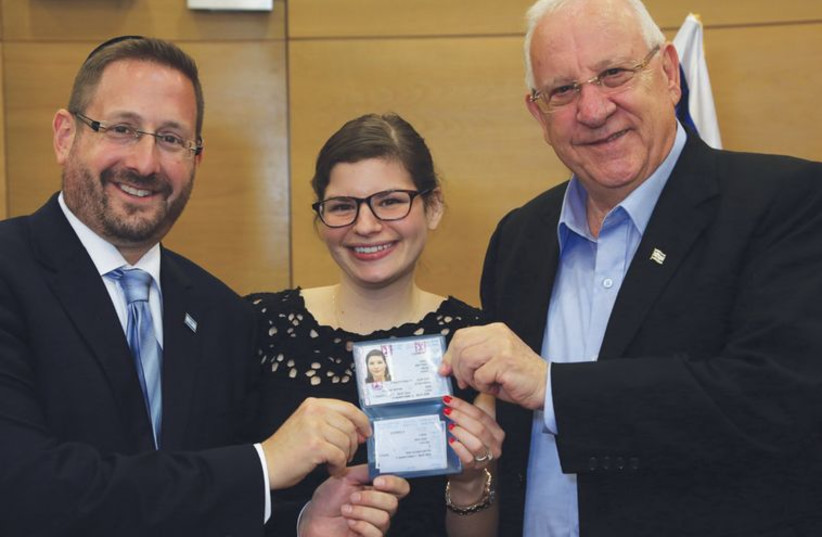 Dov Lipman and President Reuven Rivlin present a ID card to a new immigrant to Israel in July (photo credit: SASSON TIRAM)