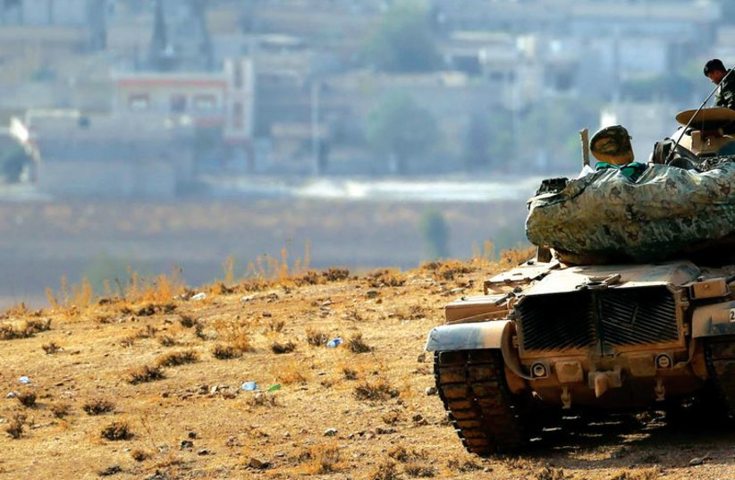 A Turkish soldier atop a tank watches as Islamic State jihadis advance on the Syrian Kurdish town of Kobani, October 10. (photo credit: UMIT BEKTAS / REUTERS)