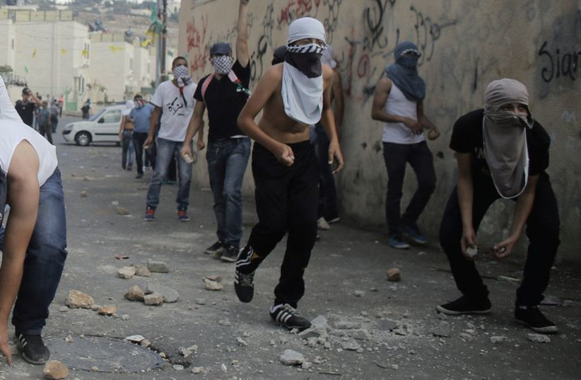 Palestinian youths hurl stones during clashes with Israeli police in the East Jerusalem neighborhood of Wadi Joz, September 7. (photo credit: AMMAR AWAD / REUTERS)