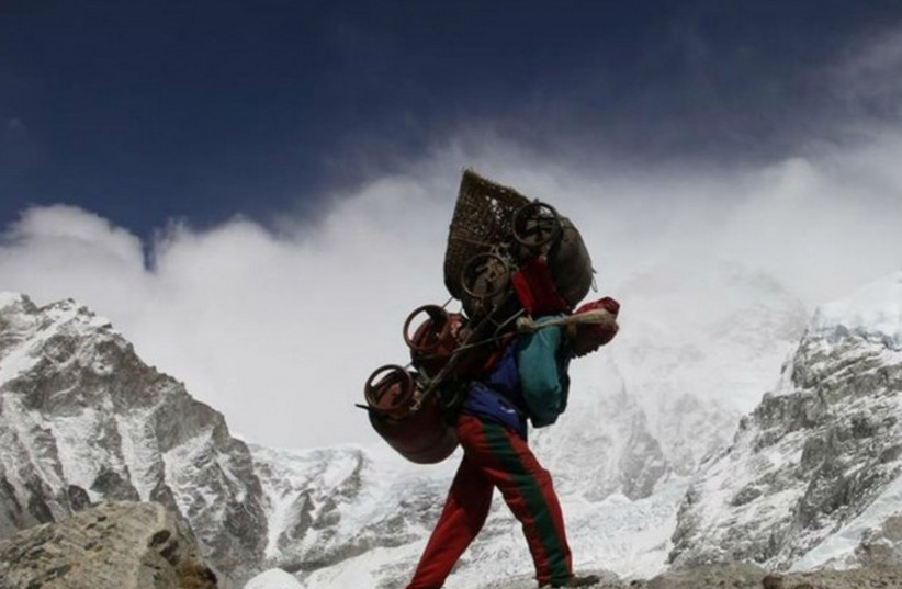 A Nepalese porter walks with his load from Everest base camp in Nepal (photo credit: REUTERS)