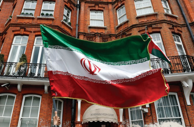 A MAN holds a flag outside the Iranian consulate in central London. (photo credit: REUTERS)