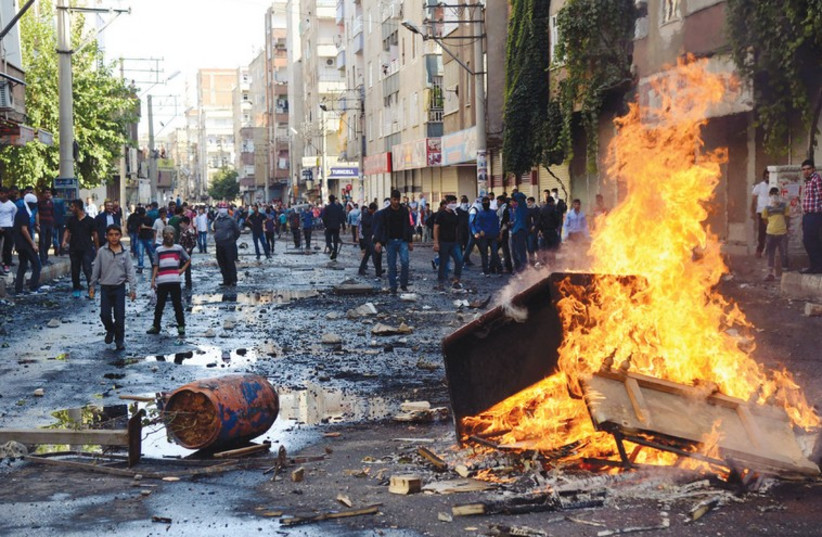 KURDISH PROTESTERS set fire to a barricade set up to block the street as they fight with riot police in Diyarbakir in southeastern Turkey (photo credit: REUTERS)