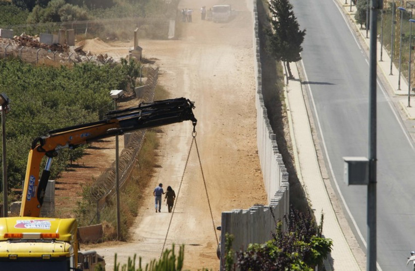 A wall at the Israeli side is seen under construction from the southern Lebanese village of Kfar Kila near the Lebanese-Israeli border (photo credit: REUTERS)