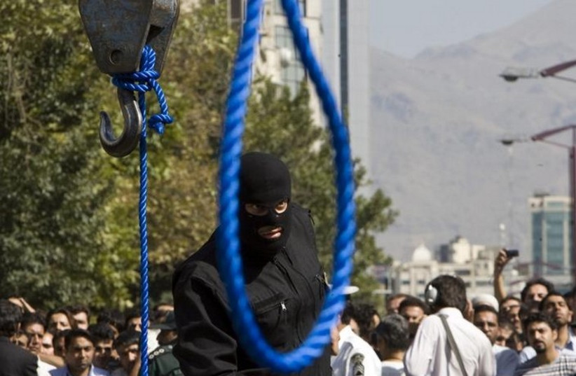 An Iranian policeman before a hanging [File] (photo credit: REUTERS)