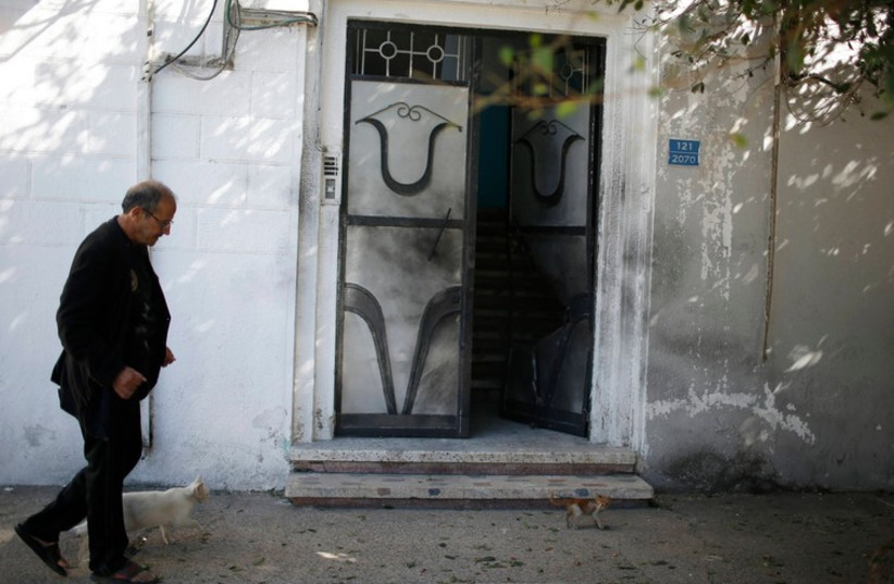 A man walks past a damaged door of a Fatah official's home after an explosion in Gaza City November 7, 2014 (photo credit: REUTERS)