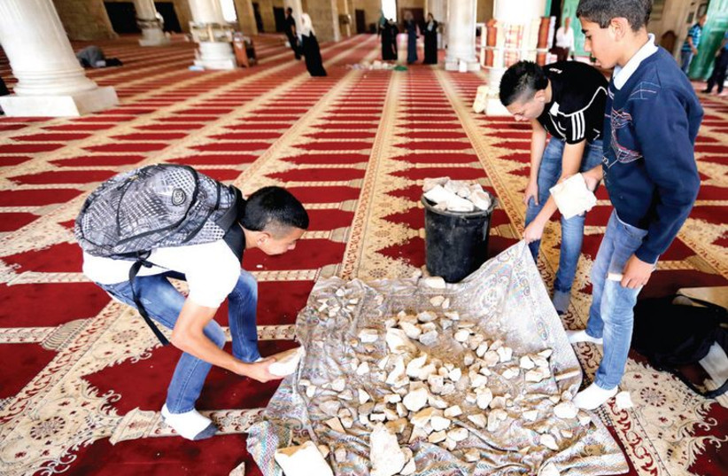 Palestinian youth inside the Al-Aqsa mosque in Jerusalem’s Old City gather stones that were used during clashes with police (photo credit: AMMAR AWAD / REUTERS)