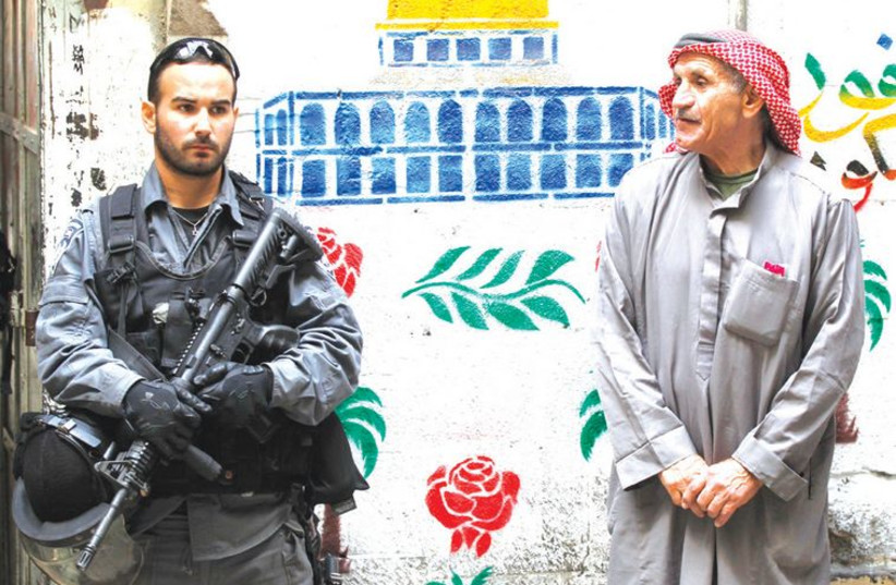 An Israeli policeman and a Palestinian in Jerusalem’s Old City (photo credit: FINBARR O'REILLY / REUTERS)