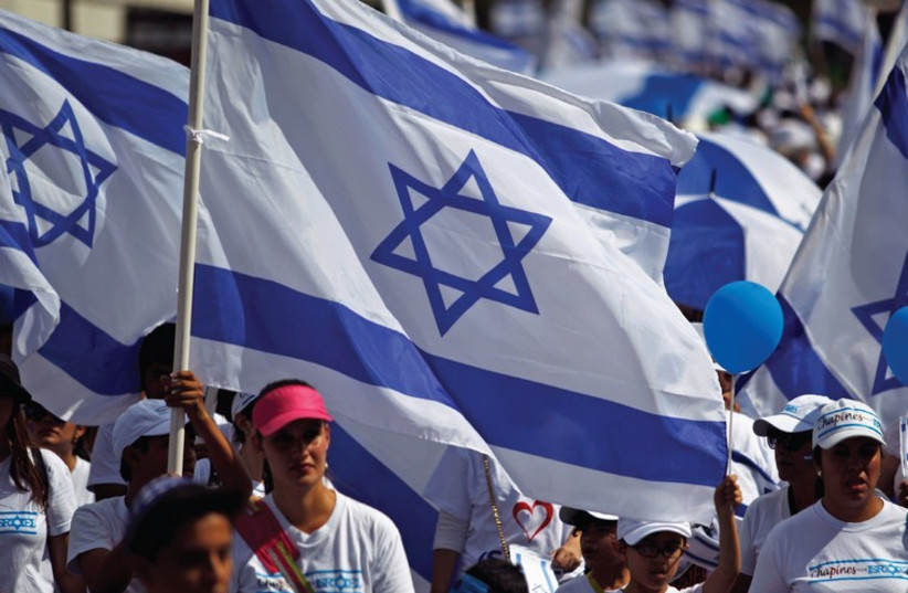 People waving Israeli flags march in a pro-Israeli demonstration in support of Israel in August 2014. (photo credit: REUTERS)