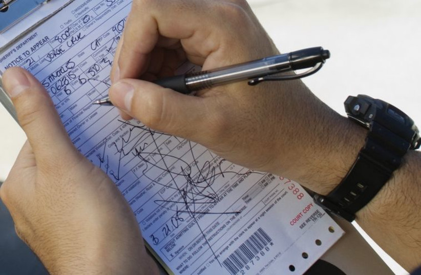 Police officer writing a ticket (illustrative photo) (photo credit: INGIMAGE)