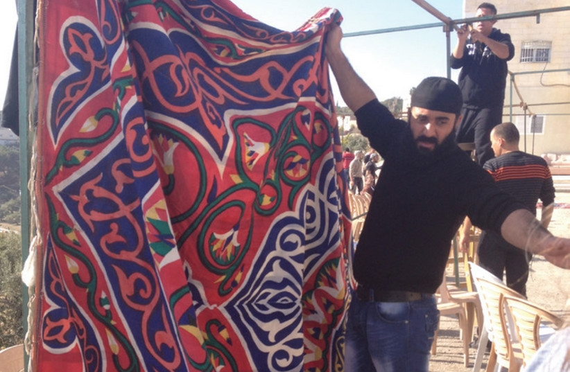A man puts up a curtain for the mourners tent for the terrorists.  (photo credit: SETH J. FRANTZMAN)