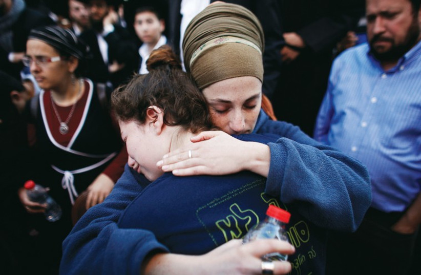 People comfort each other during the funeral of Aryeh Kopinsky, Calman Levine and Avraham Shmuel Goldberg in Jerusalem. (photo credit: REUTERS)