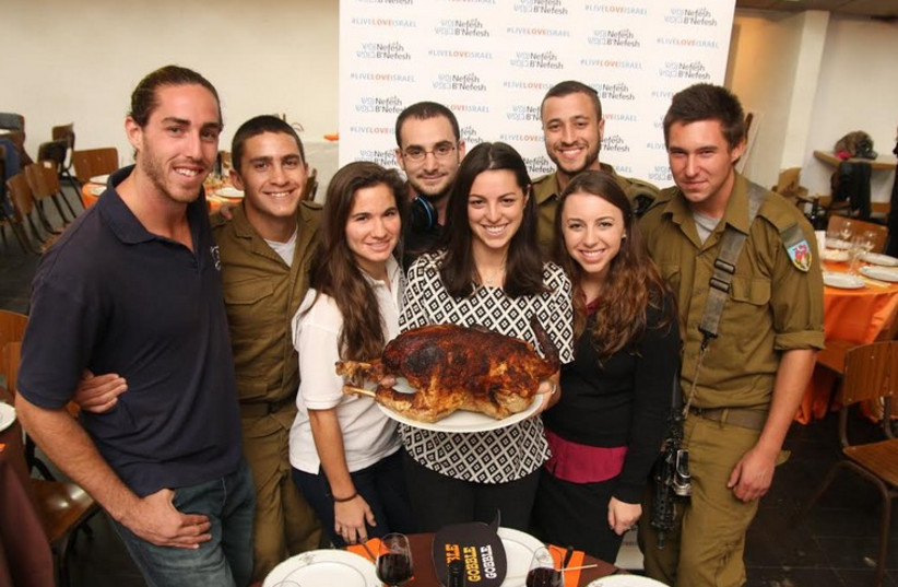 Lone soldiers and friends prepare to dig in to a turkey dinner at last Thursday’s eighth Thanksgiving gathering sponsored by Nefesh B’Nefesh in Tel Aviv, under the theme, ‘My Big Fat TLV Thanksgiving’ (photo credit: YONIT SHILLER)